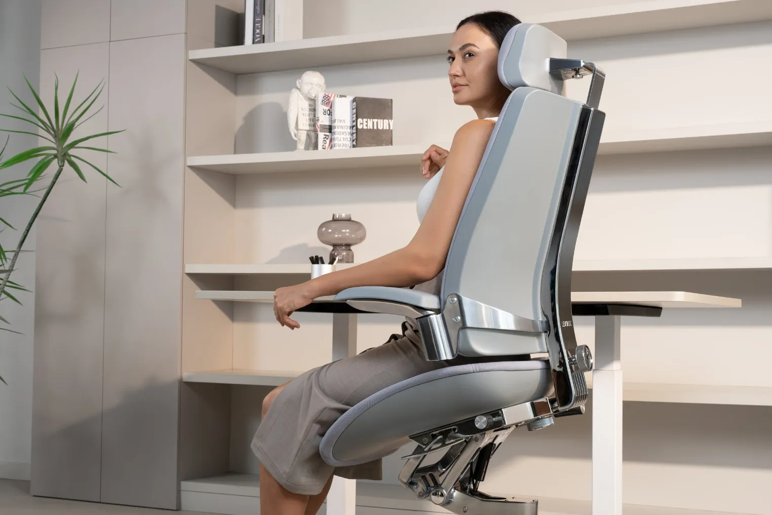 Woman seated in a Cosmic Gray Vision Chair, with the T-Mech mechanism visible beneath the seat