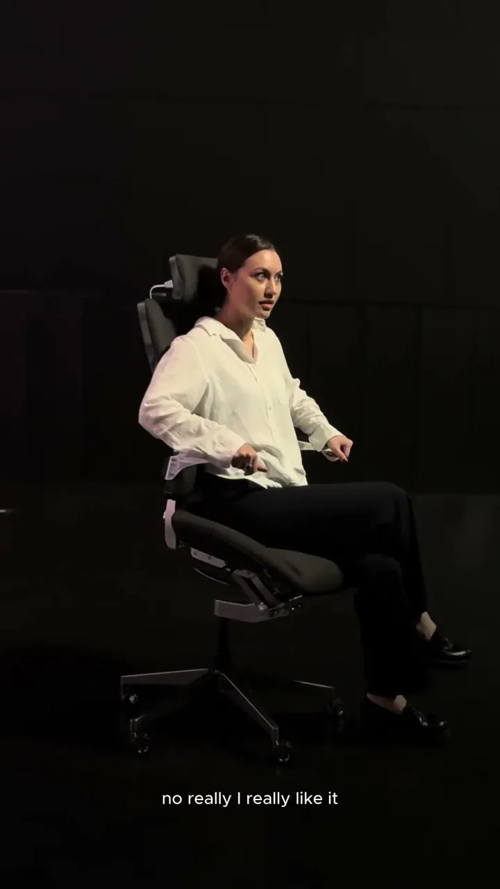 A woman trying the Vision Chair against a dark studio background