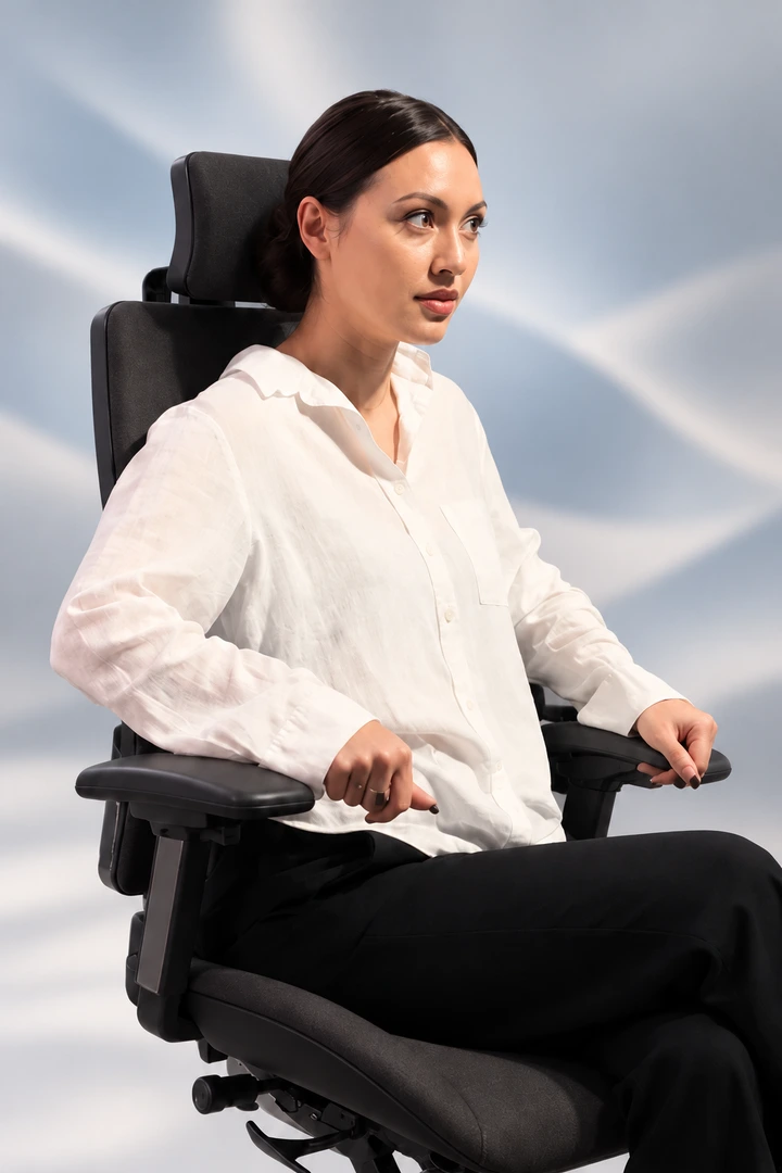 A woman trying the Vision Chair against a dark studio background